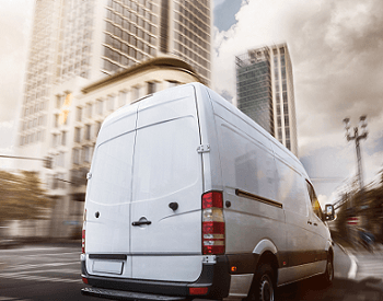 white commercial van driving through a city the background is blurred